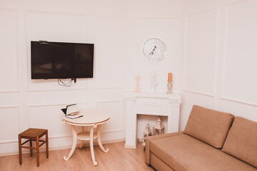 Interior of the room with white walls. Table, sofa, TV and fireplace in the room