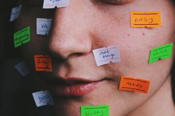 close up portait of young womans face with price tag labels with words as gender roles, social norms, stereotypes, taboos society puts on women  - obrazy, fototapety, plakaty