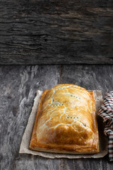 Homemade salmon wellington with spinach and mushrooms on rustic wooden table