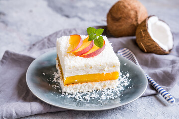 Coconut dessert with peach filling, topped with fresh fruit slices