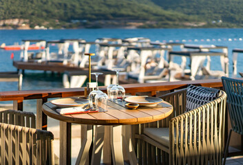 Restaurant with sea view. Plates, glasses and cutlery on wooden table