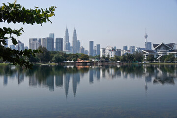 Naklejka premium Petronas Twin Towers, KL Tower, and Istana Budaya (opera house) viewed across the waters of Titiwangsa Lake, Kuala Lumpur, Malaysia
