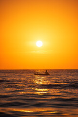 Fisherman sailling with his boat on beautiful sunrise over the sea