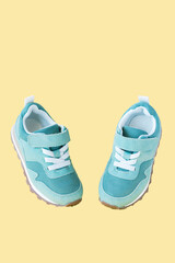 Green sneakers on yellow pastel background. Minimal concept for sport and activity.