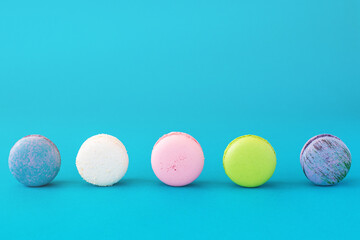 Colourful french macarons on blue pastel background. Sweet concept.
