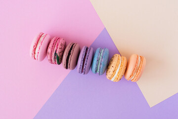 Colourful french macarons in a row on pastel background. Sweet minimal concept.