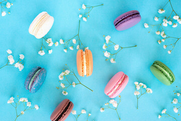 Colourful french macarons on pastel floral background. Romantic, minimal composition.