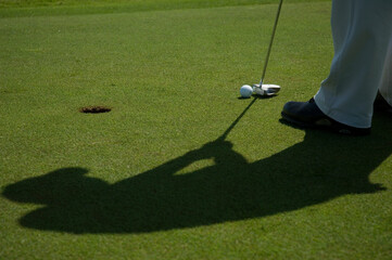 Detalhe de taco de golf com a bola, gramado e o buraco. Esporte ao ar livre.