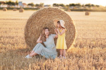Naklejka na ściany i meble Mother and daughter near bales of wheat