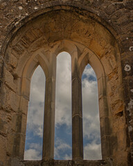 Fototapeta na wymiar arches of the castle window with blue sky and clouds