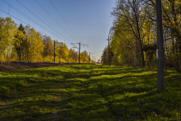 A railway in the rays of the setting sun, a path along the railway