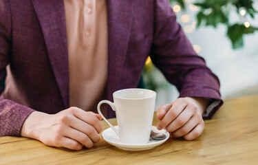 Close-up of male hands and a white cup with a plate. Lunch break. Tasty coffee
