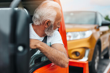 Handsome senior man working in towing service on the road. Roadside assistance concept..