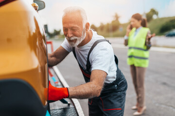 Handsome senior man working in towing service on the road. Roadside assistance concept...
