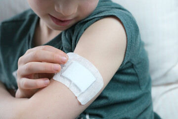 little patient in shirt, white plaster on the hand, child, boy made medical vaccine, concept of vaccination of the population against virus COVID-19