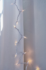 Vertical image of Soft linen curtains cover soft christmas holiday lights inside a home