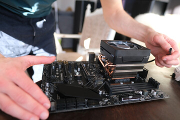 hands of young male master install cooler with copper heat pipes for the processor, other parts of pc into case, the concept of repairing equipment, assembling, upgrading a personal computer