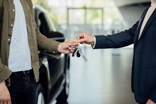 New cars. Close up of dealer giving key to new owner. Cardealer giving new car key to customer.