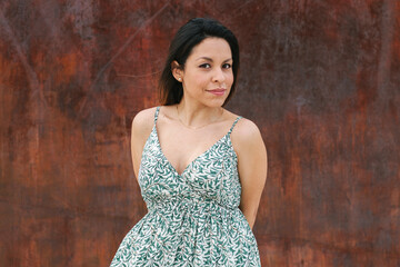 Portrait of a latin woman, smiling, looking at the camera. With a red wall in the background.