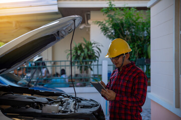 Asian engineer holding digital tablet. mechanic in uniform Check Car problem. Checking engine with tablet. 5 Generation wireless technology.