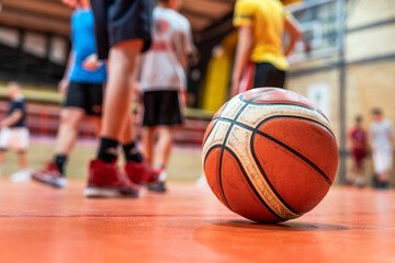 Basketball ball on the floor in sport gym on the court selective focus with blurred feet of unknown...