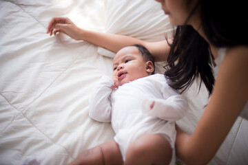 Portrait of beautiful young asian mother looking her newborn baby sleep in bed. Healthcare and medical love lifestyle mother's day concept