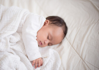 Infants are looking forward in an upside-down position on a white bed, the evolution of Baby girl in the age up to 6 months./Selected focus