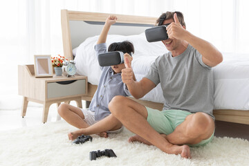 Father and his mixed-race son wearing vr virtual reality device to play a game together with fun and happy in bedroo
