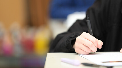A close up isolated students hand holding a pen writing during class, exam or lesson time at...