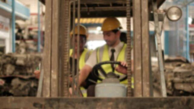 Blur focus VDO: Caucasian male forklift driver waits for a black female engineer to check engine spare parts stock in warehouses of industrial factories. And when she arrived, he drove backward.