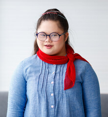 Portrait of a young down syndrome girl wearing eyeglasses in beautiful and colorful clothes looking...
