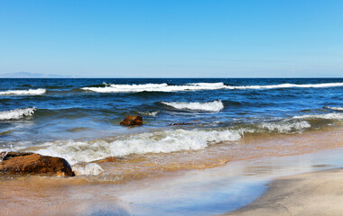 Baikal Lake in summer. Beautiful landscape with waves on the sandy beach of the Barguzinsky Bay on a sunny windy day. Summer holidays and travel. Natural seaside background
