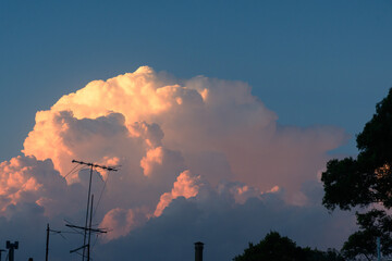 Striking reddish clouds at sunset in a sky with silhouetted antennas and rooftops