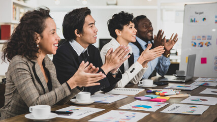 Business men and women of different nationalities were clapping their hands happily and smiling. In the meeting room at the office. Concept diversity meeting happy smilling.