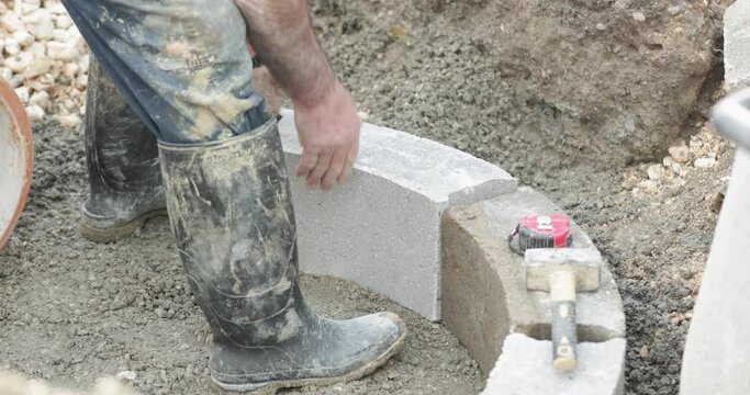 Construction Worker Fixes The Concrete Brick Using A Brick Hammer At Construction Site In Portugal. close up