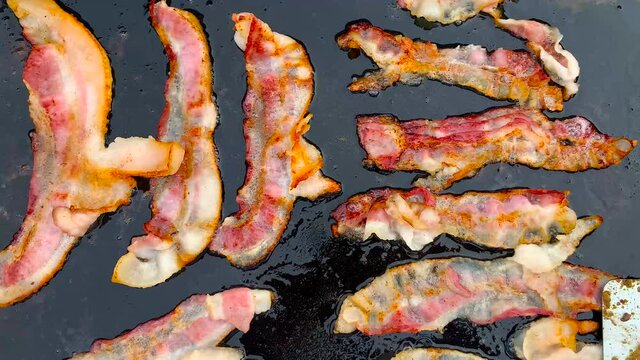 Sizzling bacon on a blackstone griddle.