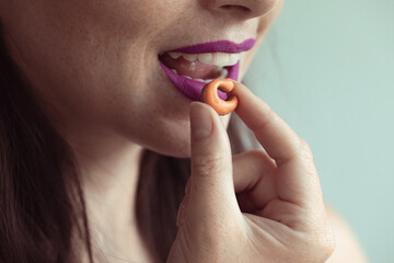 bouche souriante avec rouge à lèvres mauve ouverte avec main qui tient un comprimé en forme de C pour représenter la vitamine