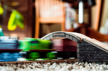 selective focus on wood toy train set bridge with motion blurred locomotive passing under