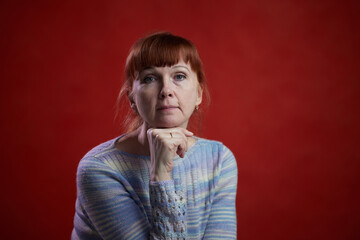 portrait of an adult redhead woman looking directly on a gray background