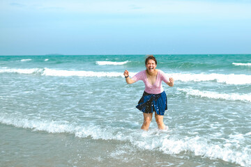 Young Asian woman in a swimsuit is playing water at the beach.