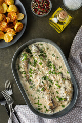 Stewed hake in a creamy sauce with baked potatoes, delicious hearty lunch, top view