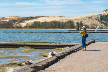 Tourist girl taking photos of the desert dunes of the Curonian Spit in Nida fishermen's village, Lithuania, Europe