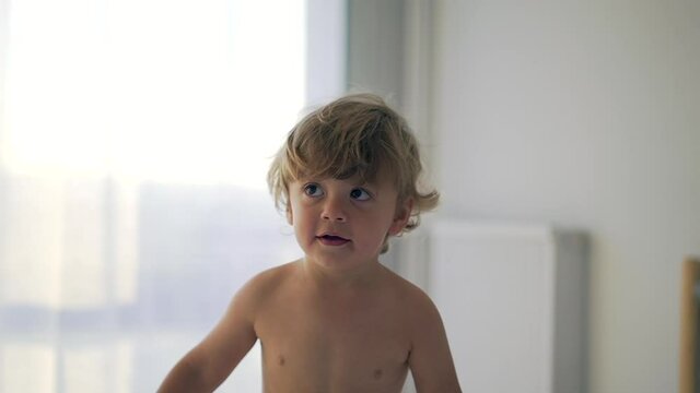 Happy baby toddler bouncing in bed in morning. Infant child jumping up and down