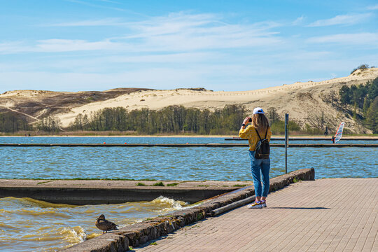 Tourist girl taking photos of the desert dunes of the Curonian Spit in Nida fishermen's village, Lithuania, Europe