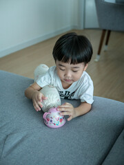 Asian boy playing on sofa holding bolster
