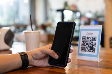 Man's hands are using  the phone to scan the qr code to select food menu. Scan to get discounts or pay for food. The concept of using a phone to transfer money or paying money online without cash.