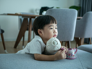 Asian boy playing on sofa holding bolster