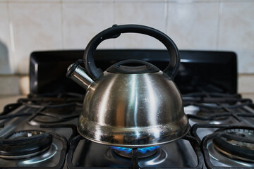 Una tetera metálica de plata en una estufa de gas en la cocina