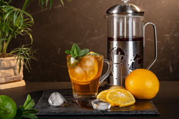 Iced tea with lemon and mint. Cool iced tea. Thirst quenching tea. Front view. Slicing lemon.