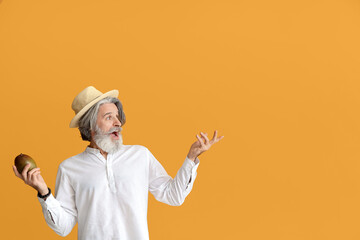 Senior man with mango showing something on color background